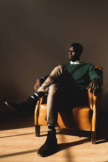 Man sitting in leather armchair looking sideways - FMOF00846