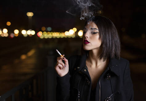 Porträt einer rauchenden jungen Frau bei Nacht - LJF01138