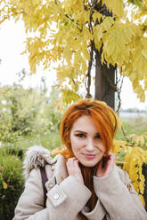 Portrait of smiling young woman with orange dyed hair in autumn - LJF01143