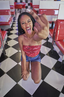 Young woman with braided hairstyle doing a sign with her heart finger to the camera - VEGF01204