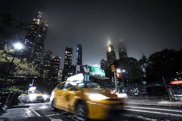 USA, New York, Gelbes Taxi auf der Straße bei Nacht - DAMF00228