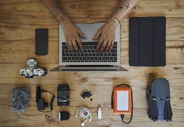 Person, die an einem Tisch mit Fotoausrüstung sitzt und einen Laptop benutzt, Blick von oben - VEGF01216