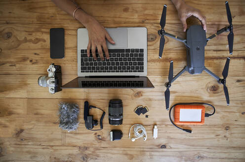 Person, die an einem Tisch mit Fotoausrüstung sitzt und einen Laptop benutzt, Blick von oben - VEGF01218