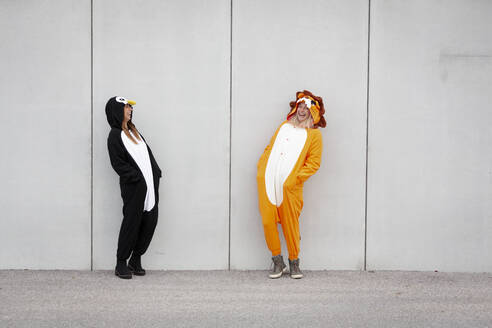 Zwei Frauen im Pinguin- und Löwenkostüm vor einer Betonwand - HMEF00705
