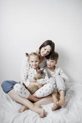 Mother with two kids and a cat sitting on bed - EYAF00765