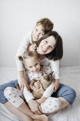 Mother with two kids and a cat sitting on bed - EYAF00766