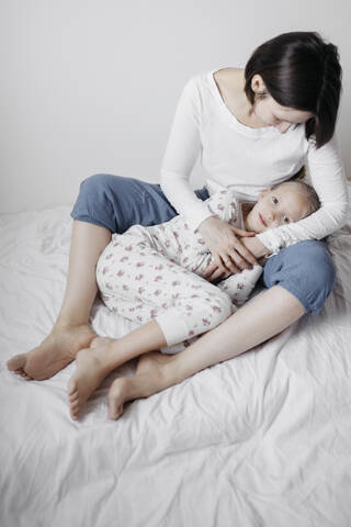 Mutter, die ihre Tochter im Bett umarmt, lizenzfreies Stockfoto