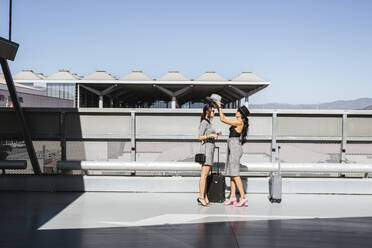 Zwei modische junge Frauen mit Gepäck auf dem Parkdeck des Flughafens - LJF01179