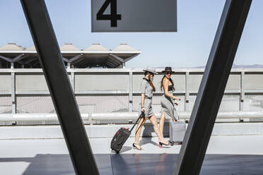 Zwei modische junge Frauen mit Gepäck auf dem Parkdeck des Flughafens - LJF01181