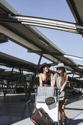 Two happy fashionable young women with baggage at the airport parking deck - LJF01182