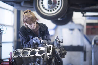 Weiblicher Automechaniker, der ein Auto in einer Reparaturwerkstatt repariert - SGF02530