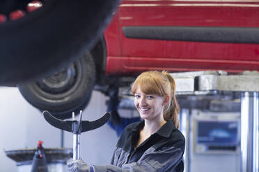 Lächelnde Automechanikerin in einer Reparaturwerkstatt - SGF02532