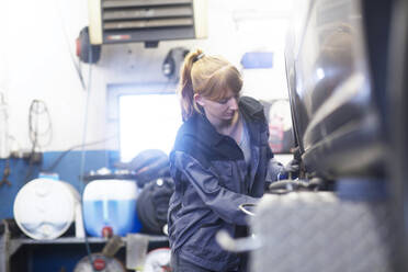 Automechanikerin bei der Arbeit in einer Reparaturwerkstatt - SGF02536