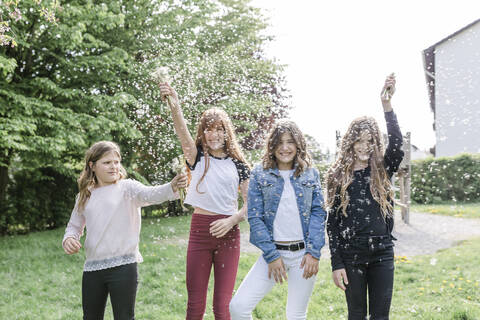 Four happy girls playing with dandelion seeds stock photo