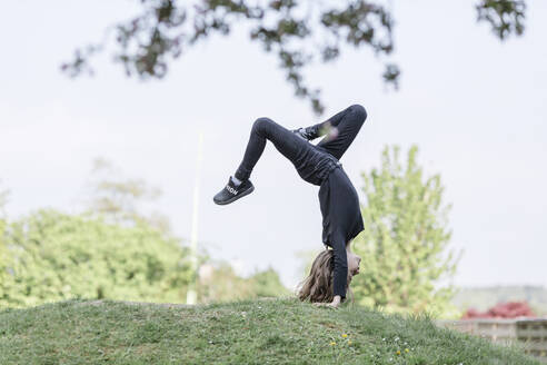 Mädchen macht einen Handstand auf einer Wiese - STBF00518