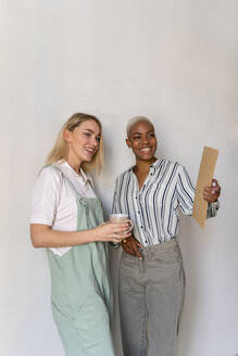 Zwei lächelnde Frauen mit Klemmbrett und Tasse Kaffee - AFVF04458