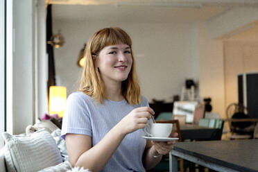 Porträt einer erdbeerblonden jungen Frau mit Nasenpiercing und einer Tasse Kaffee in einem Cafe - FLLF00362