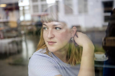 Porträt einer jungen Frau in einem Cafe, die aus dem Fenster schaut - FLLF00364