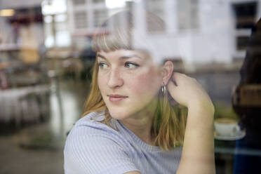 Portrait of young woman in a cafe looking out of window - FLLF00364