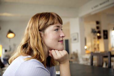 Porträt einer erdbeerblonden jungen Frau mit Nasenpiercing in einem Cafe - FLLF00365
