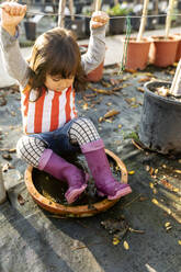 Little girl wearing Wellington Boots playing at pant nursery - VABF02483