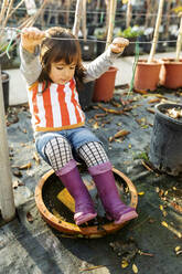 Little girl wearing Wellington Boots playing at pant nursery - VABF02484