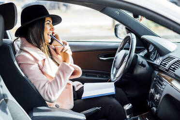 Geschäftsfrau mit Smartphone im Auto, Notebook auf dem Schoß - CJMF00205