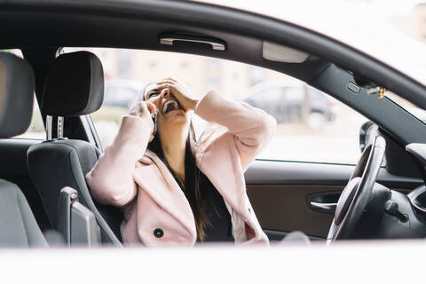 Lachende Geschäftsfrau mit Smartphone im Auto, lizenzfreies Stockfoto
