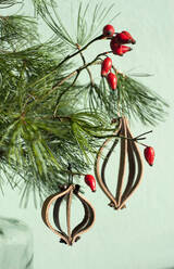 Weihnachtsschmuck aus Leder auf Kiefernzweig mit roten Hagebutten - GISF00490
