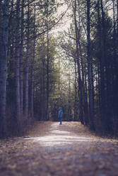 Full length of boy standing on dirt road amidst forest - CAVF70844