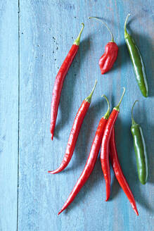 Overhead view of chili peppers on blue wooden table - CAVF70913