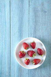Draufsicht auf Erdbeeren in einem Teller auf einem Holztisch - CAVF70917