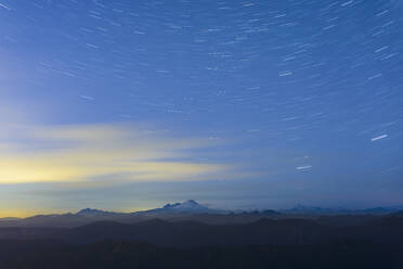 Scenic view of star trails over landscape - CAVF70933