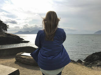 Frau mit Jacke und Blick auf den Fluss - CAVF70943