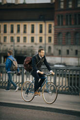 Fahrrad fahrender Geschäftsmann auf einer Brücke in voller Länge - MASF15522