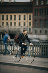 Full length of businessman riding bicycle on bridge - MASF15522