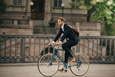 Geschäftsmann auf dem Fahrrad in voller Länge auf der Straße in der Stadt - MASF15531