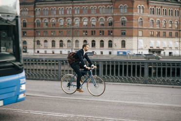 Geschäftsmann in voller Länge auf dem Fahrrad auf der Straße in der Stadt - MASF15532