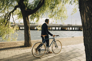 Geschäftsmann zu Fuß mit Fahrrad auf dem Gehweg in der Stadt - MASF15559