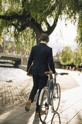 Rückansicht eines Geschäftsmannes mit Fahrrad auf einem Fußweg in der Stadt - MASF15563