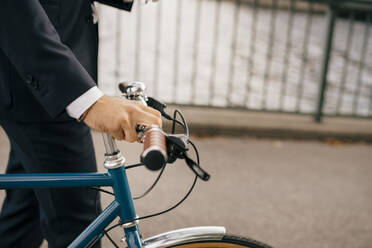 Mittelteil eines Geschäftsmannes mit Fahrrad auf einer Brücke in der Stadt - MASF15580