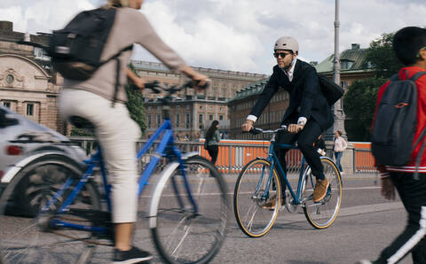 Geschäftsmann in voller Länge auf dem Fahrrad auf einer Straße in der Stadt, lizenzfreies Stockfoto