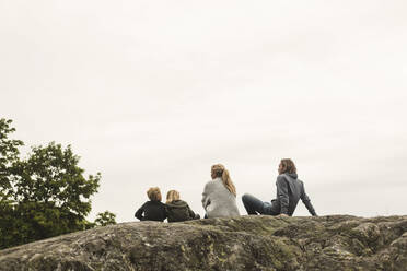 Family resting together on rock formation against clear sky - MASF15603