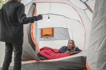 Girl talking to sister using mobile phone in tent - MASF15625