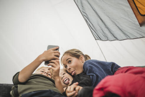 Geschwister machen ein Gesicht beim Selfie im Zelt - MASF15627