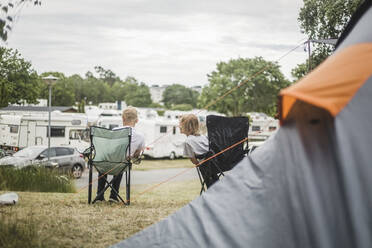 Geschwister unterhalten sich auf Stühlen auf dem Campingplatz - MASF15650