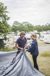 Teenagerin hilft ihrem Vater beim Aufbau des Zeltes auf dem Campingplatz - MASF15661