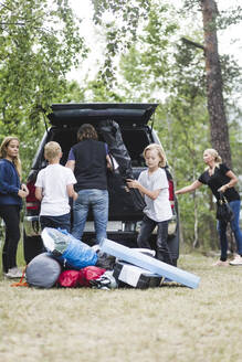 Camping-Familie beim Ausladen des Gepäcks aus dem Kofferraum eines Autos im Wald - MASF15678