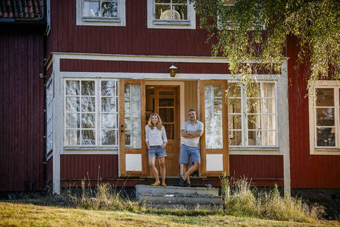 Porträt eines Paares in voller Länge, das vor der Tür einer Blockhütte steht - MASF15701