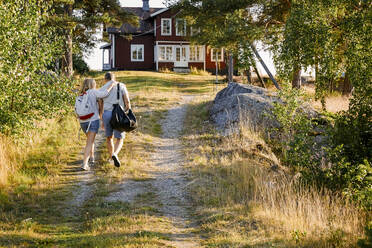 Männliche und weibliche Partner gehen in den Sommerferien auf dem Weg zum Haus - MASF15703